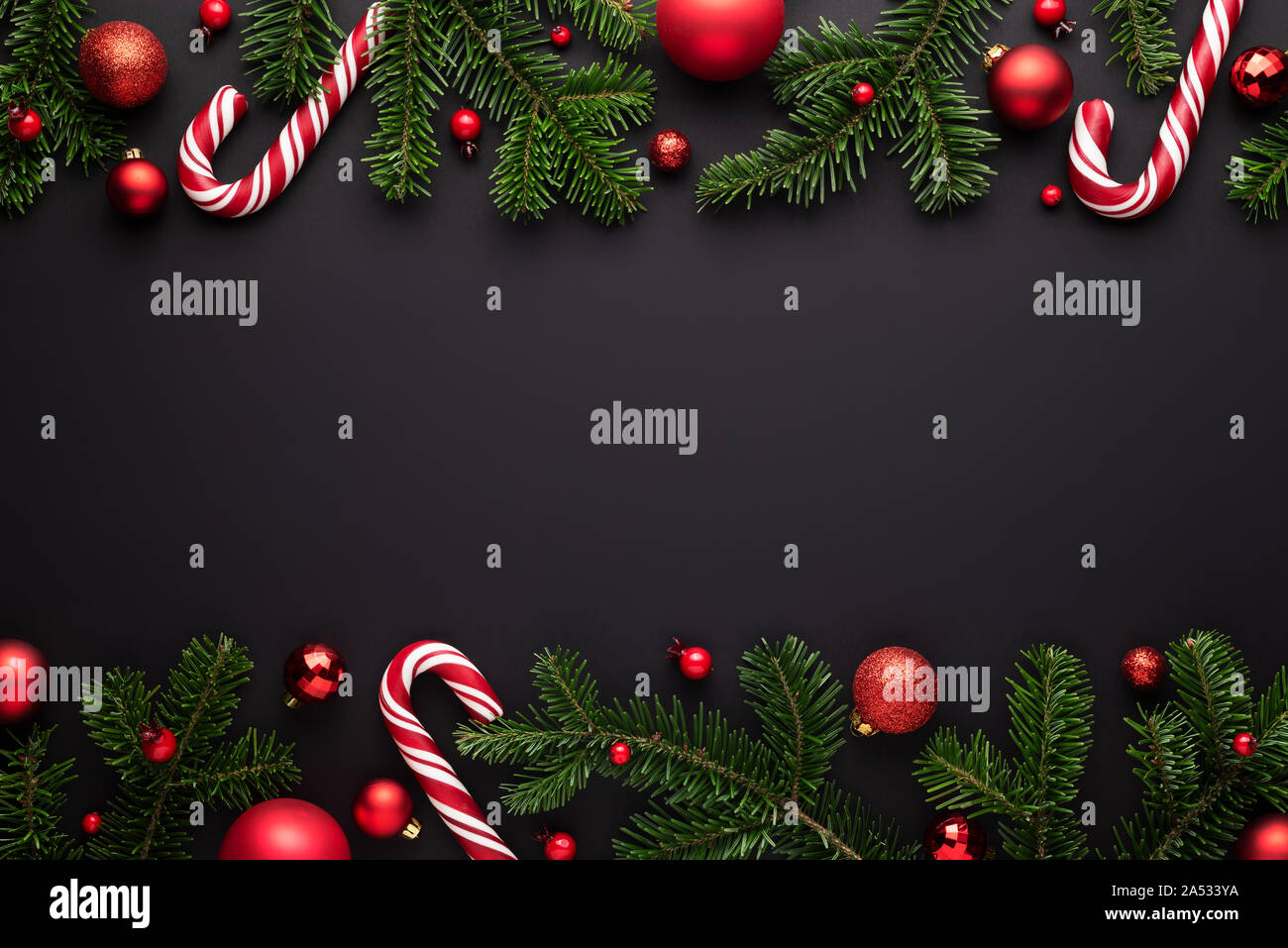 Black Christmas background. Decorative border frame of fir branches, red  Christmas balls and Candy canes Stock Photo - Alamy