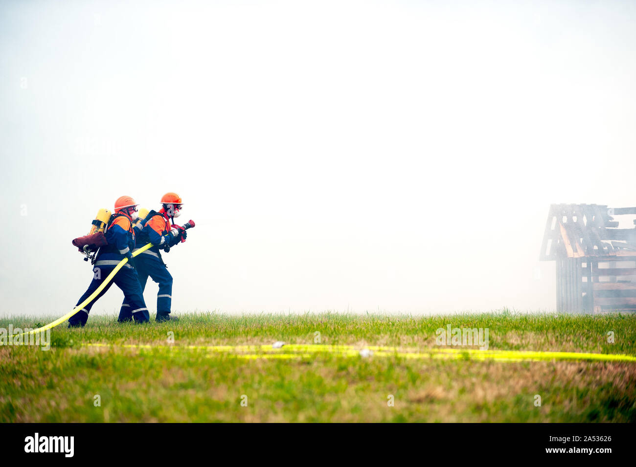 Germany, Niederstetten, Baden Wurttemberg. September 2019 Young firefighters in training with fire hose by extinguishing the fire. Stock Photo