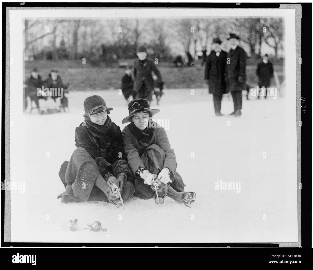 Two people seated on snow, and putting on ice skates, in the Washington, D.C., area Stock Photo