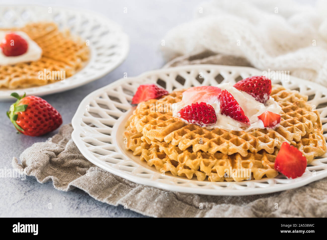 Fresh golden waffles with chopped strawberries and whipped cream on top ...