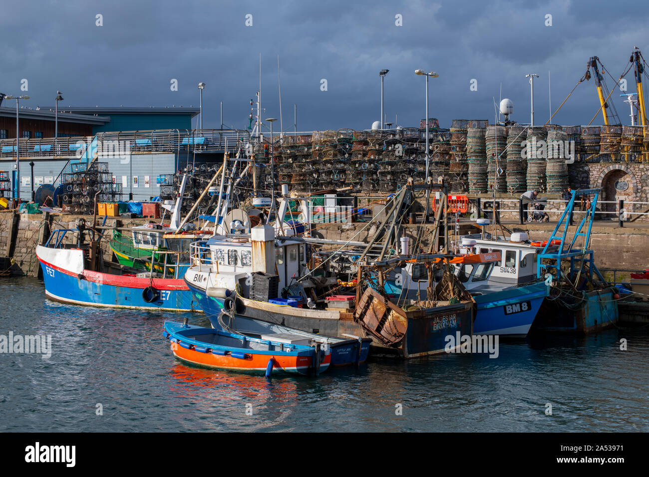 Shafts of light during the approaching storm light up the gaggle of boats in Brixham Inner Harbour in the month of October Stock Photo