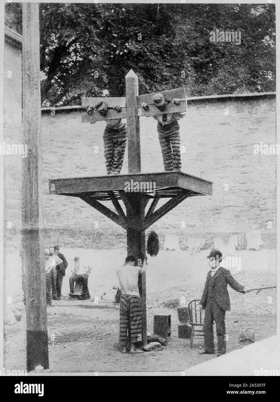 Two prisoners in pillory with another tied to whipping post below and a man with whip, at New Castle County Courthouse in Delaware Stock Photo