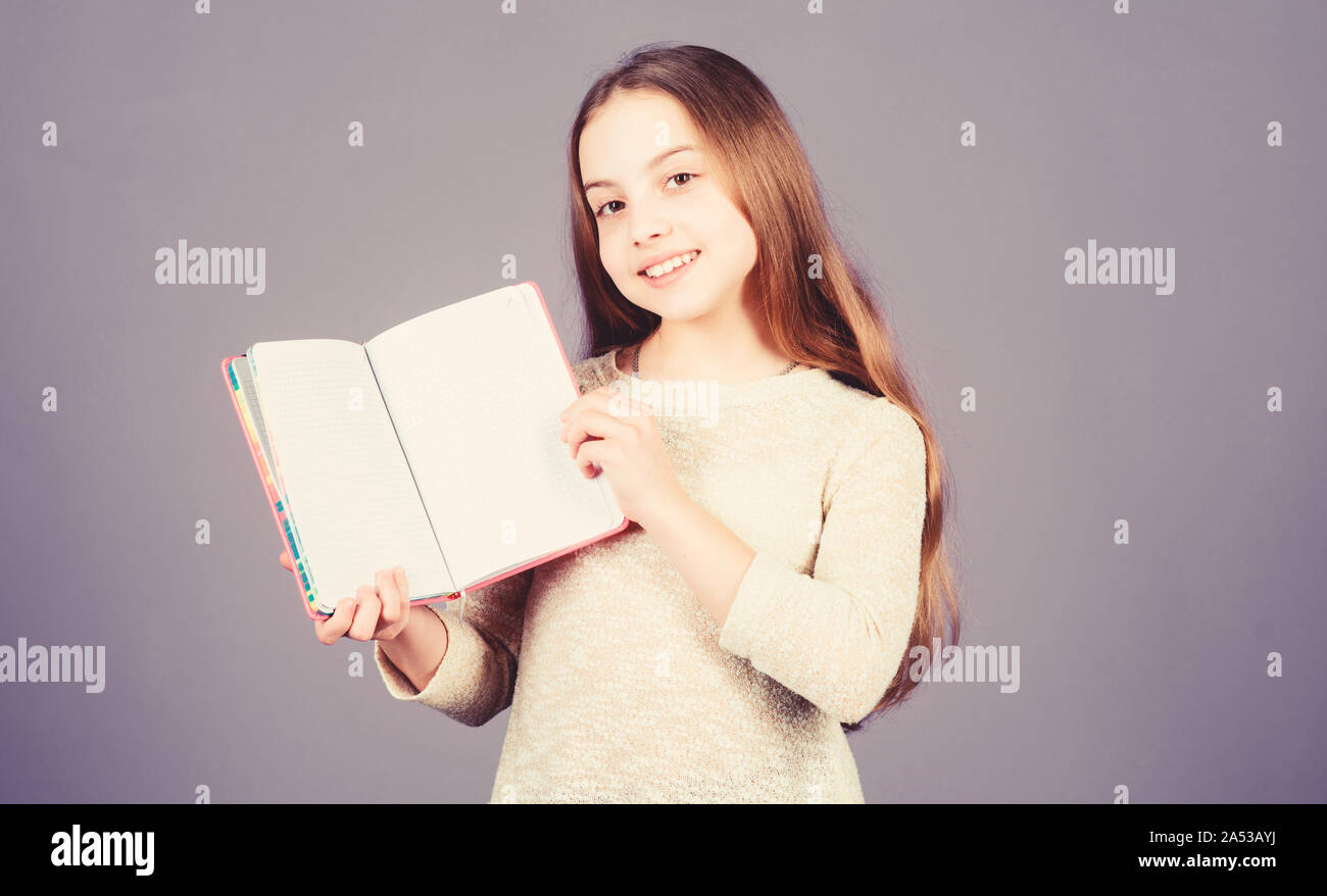 Applying her book knowledge to the real world. Adorable small girl holding open book. Cute little child with book knowledge in hands. Knowledge skills. Knowledge day or September 1, copy space. Stock Photo