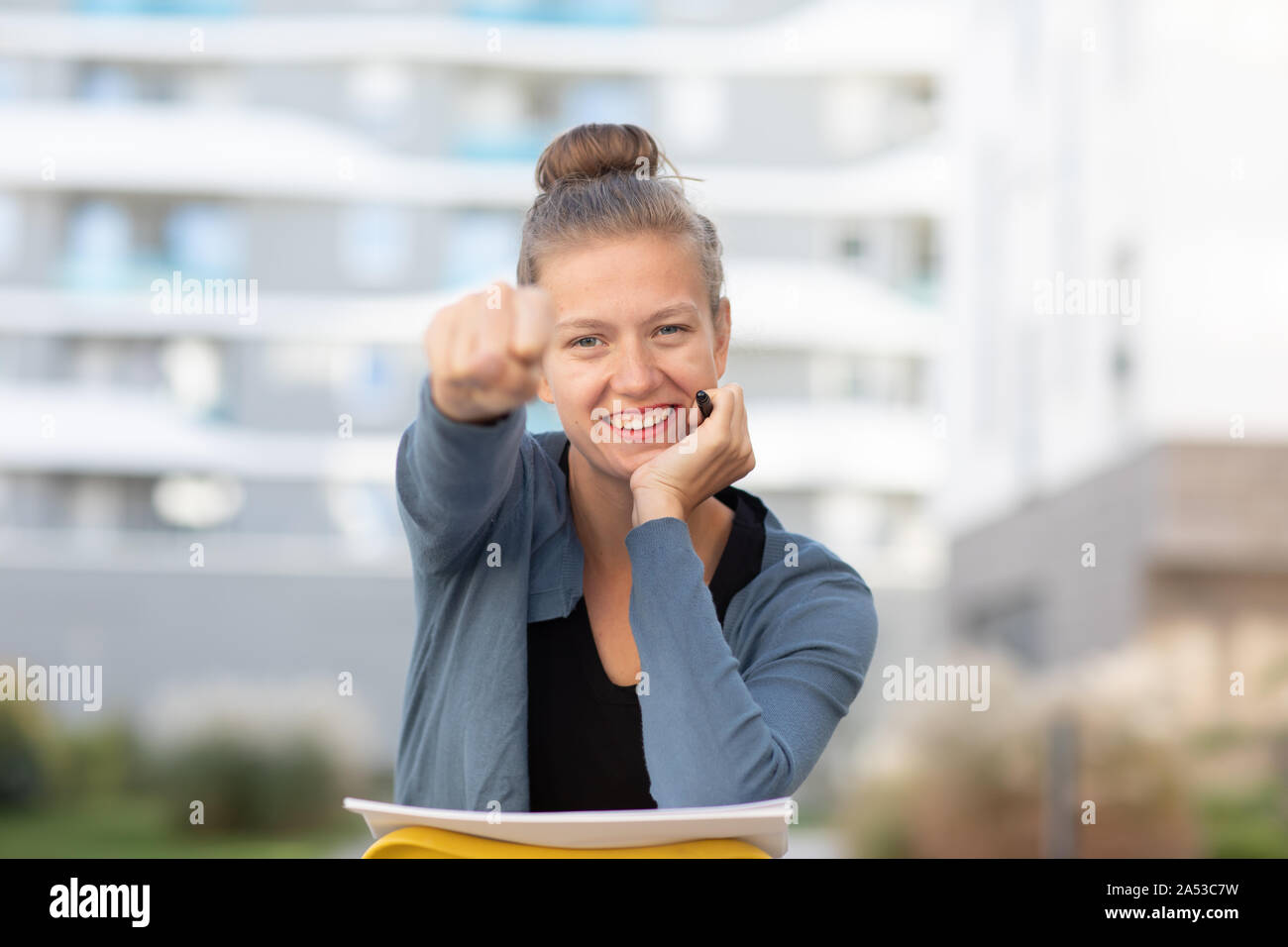 young woman outside sitting on a chair backward showing with hand Stock Photo