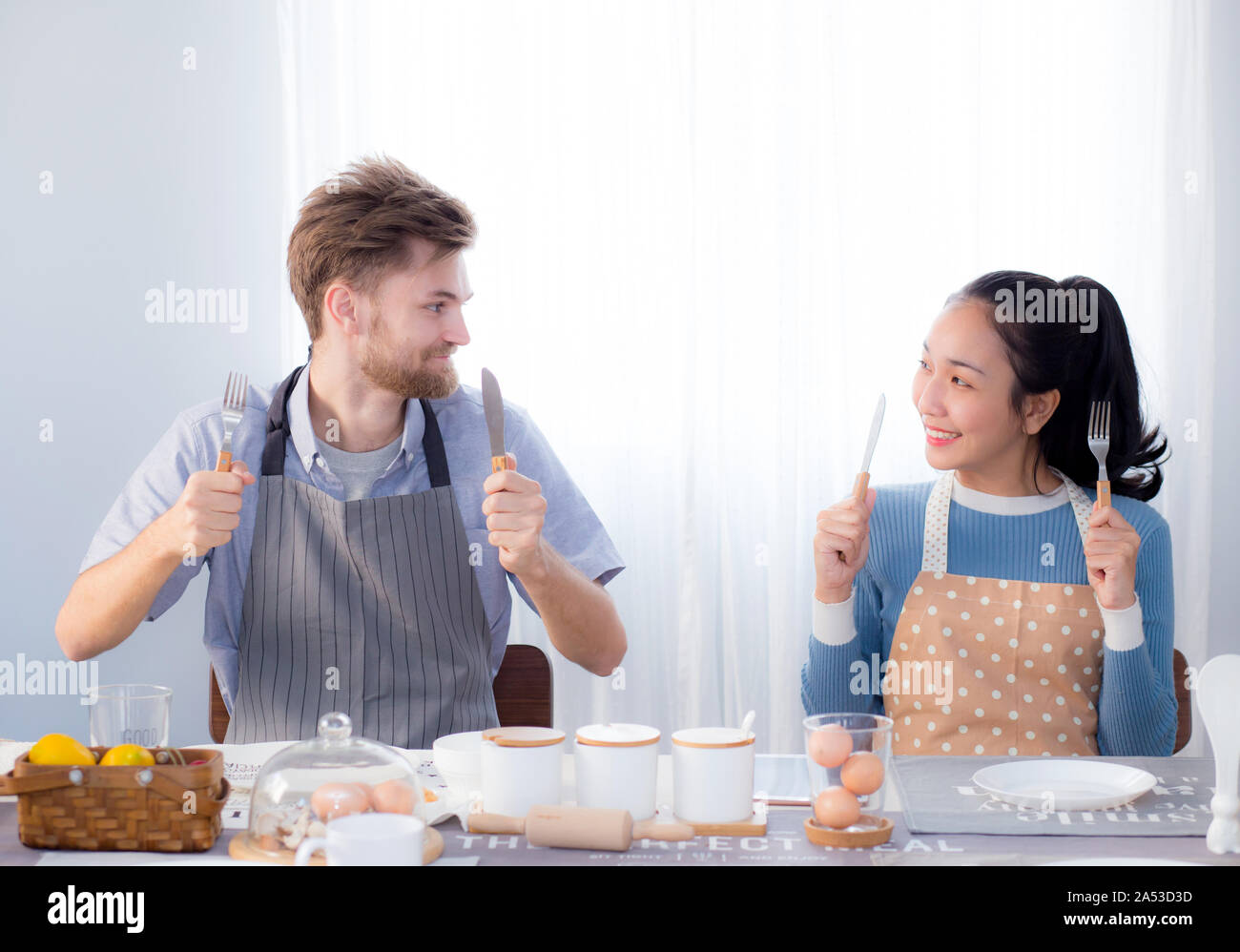 Young family couple sitting at the table in the kitchen and holding