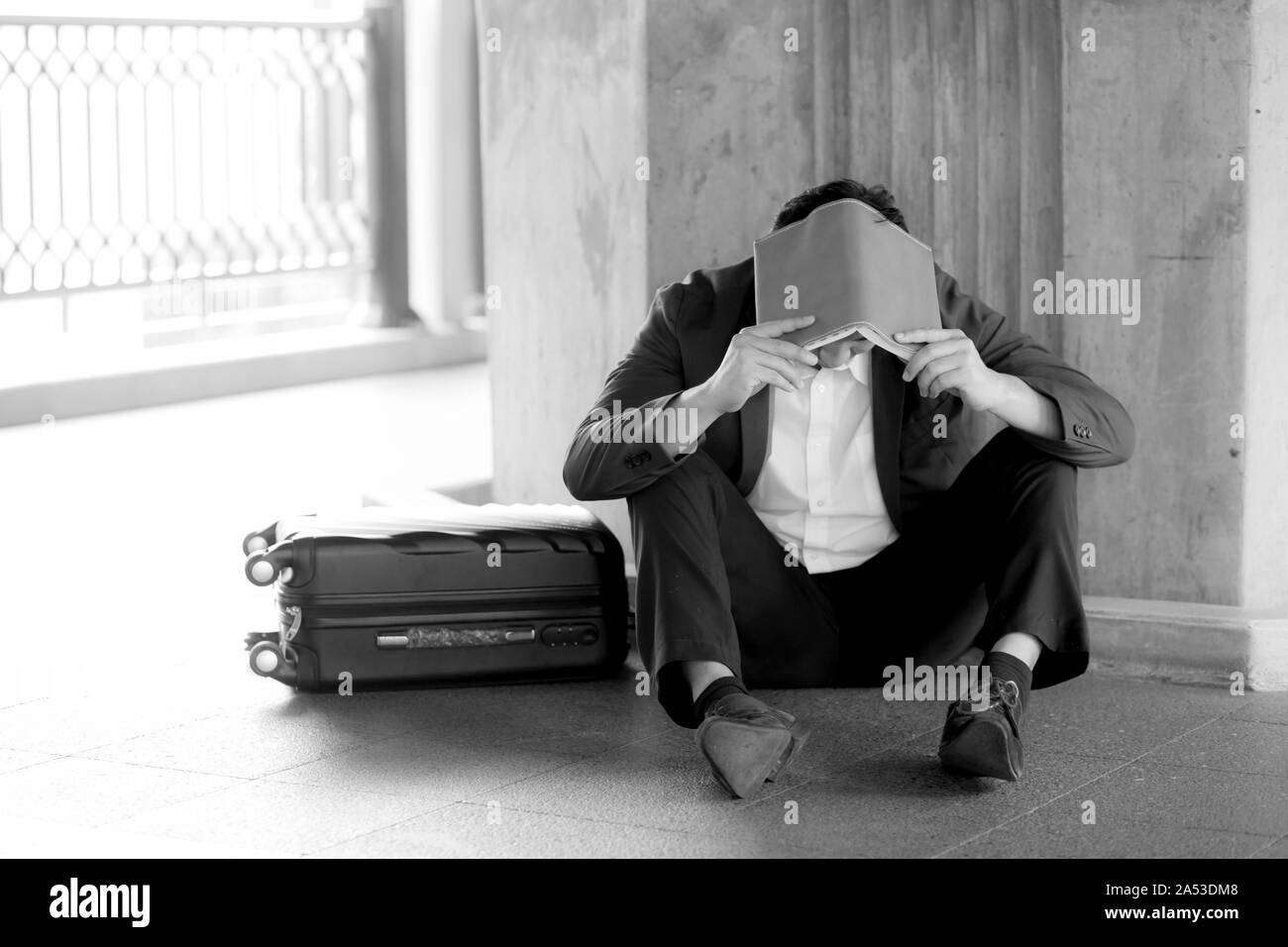 Stressed asian businessman bankrupt with sitting at outdoor and book close face black and white picture. Stock Photo