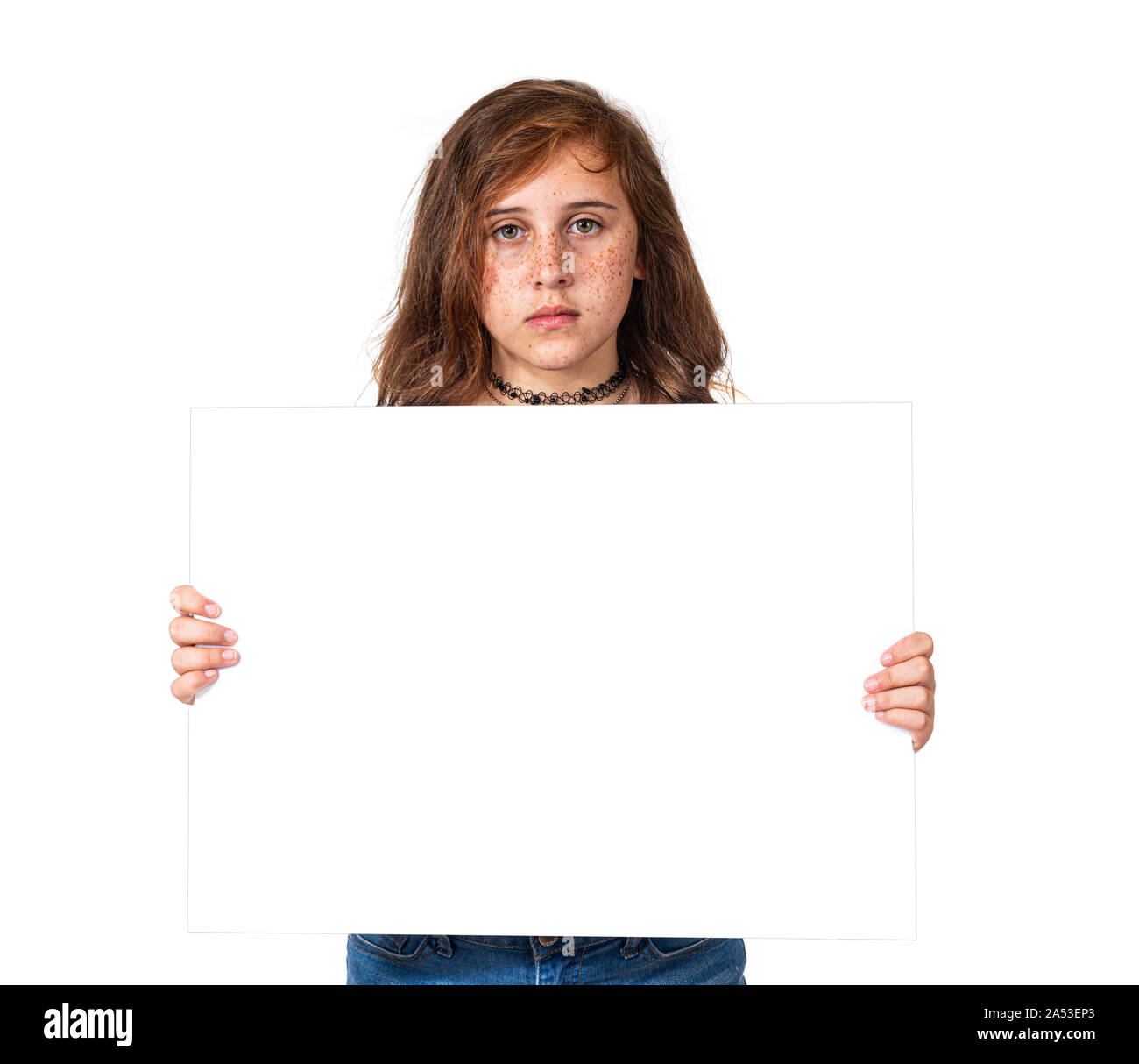 Horizontal studio shot of a serious looking pre-teen girl with freckles holding a blank white sign.  White background.  Copy space. Stock Photo