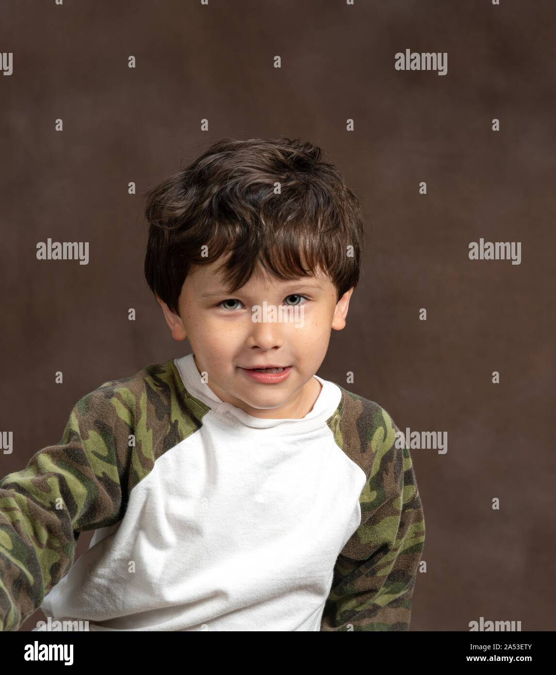 Vertical studio shot of a suspicious but cute four year old on a brown background with copy space. Stock Photo