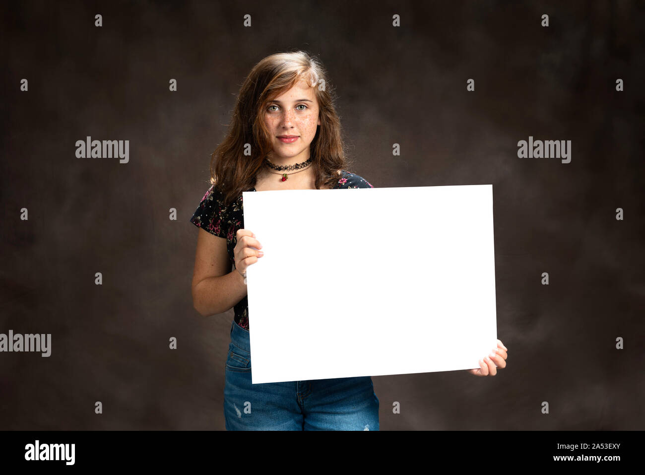 Horizontal shot of a confident pre-teen girl with freckles holding a blank sign. Stock Photo