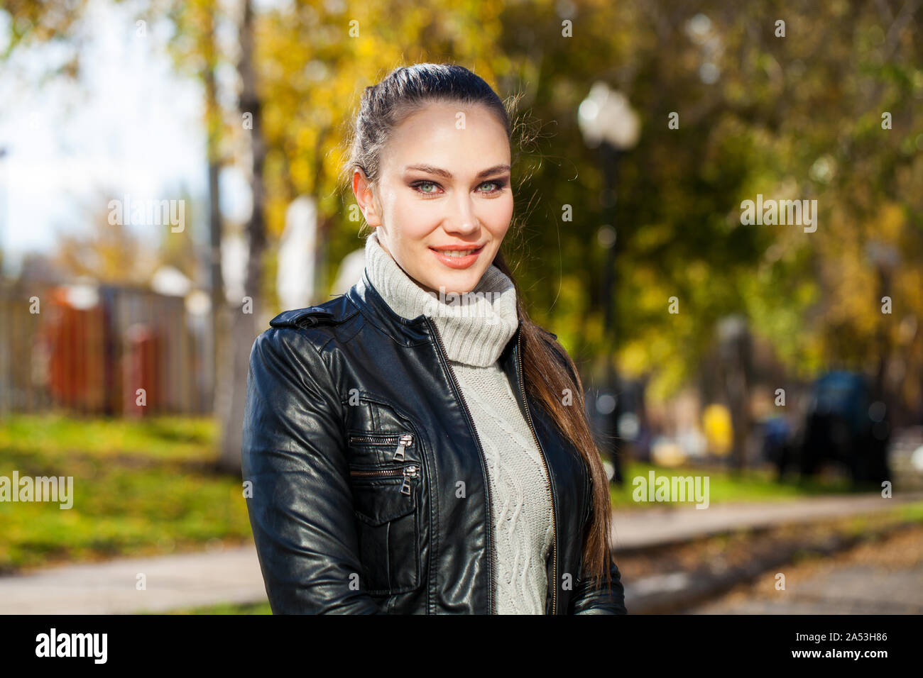 Portrait of a young beautiful brunette woman in a black leather jacket ...