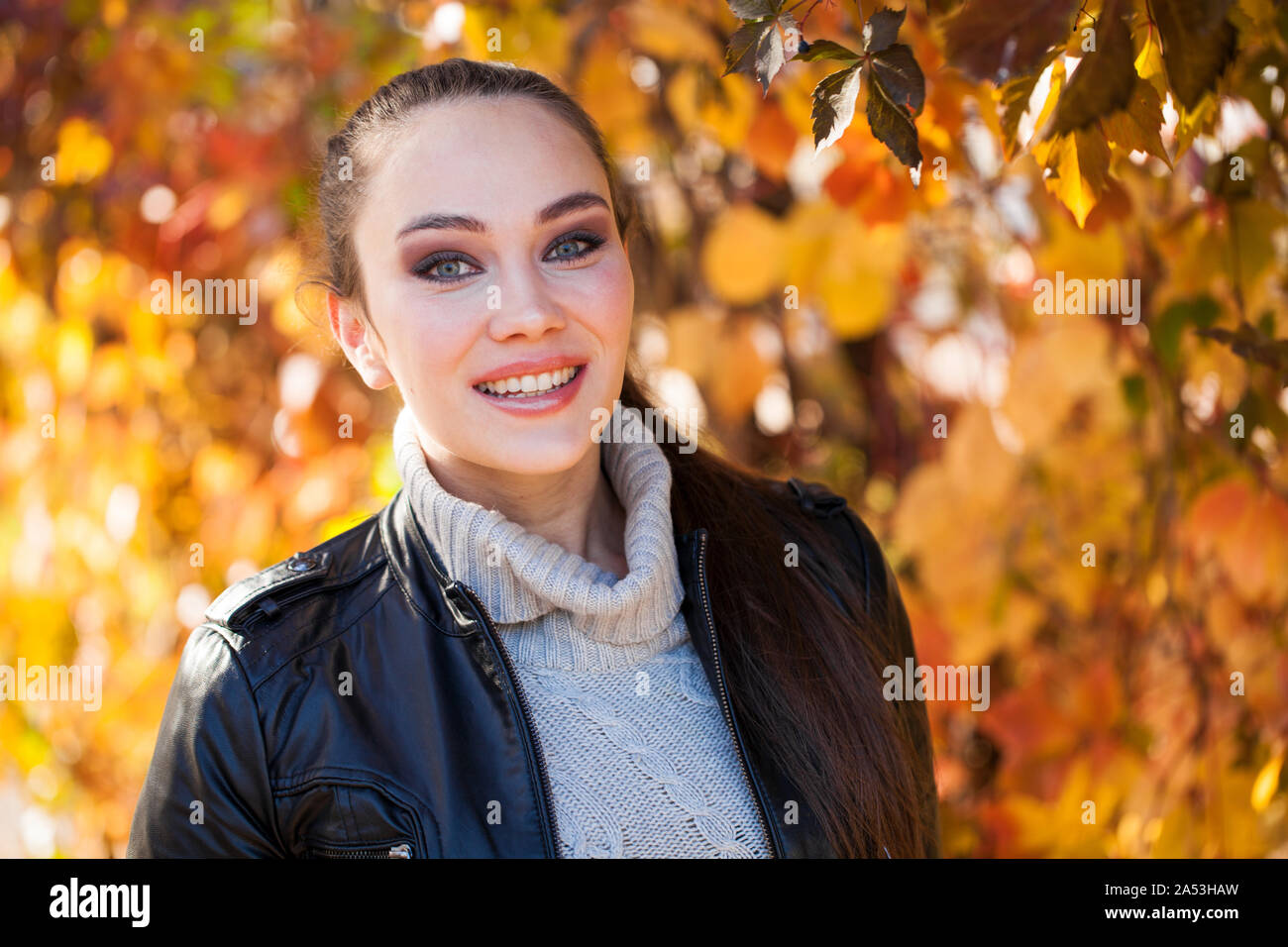 Portrait of a young beautiful brunette woman in a black leather jacket ...