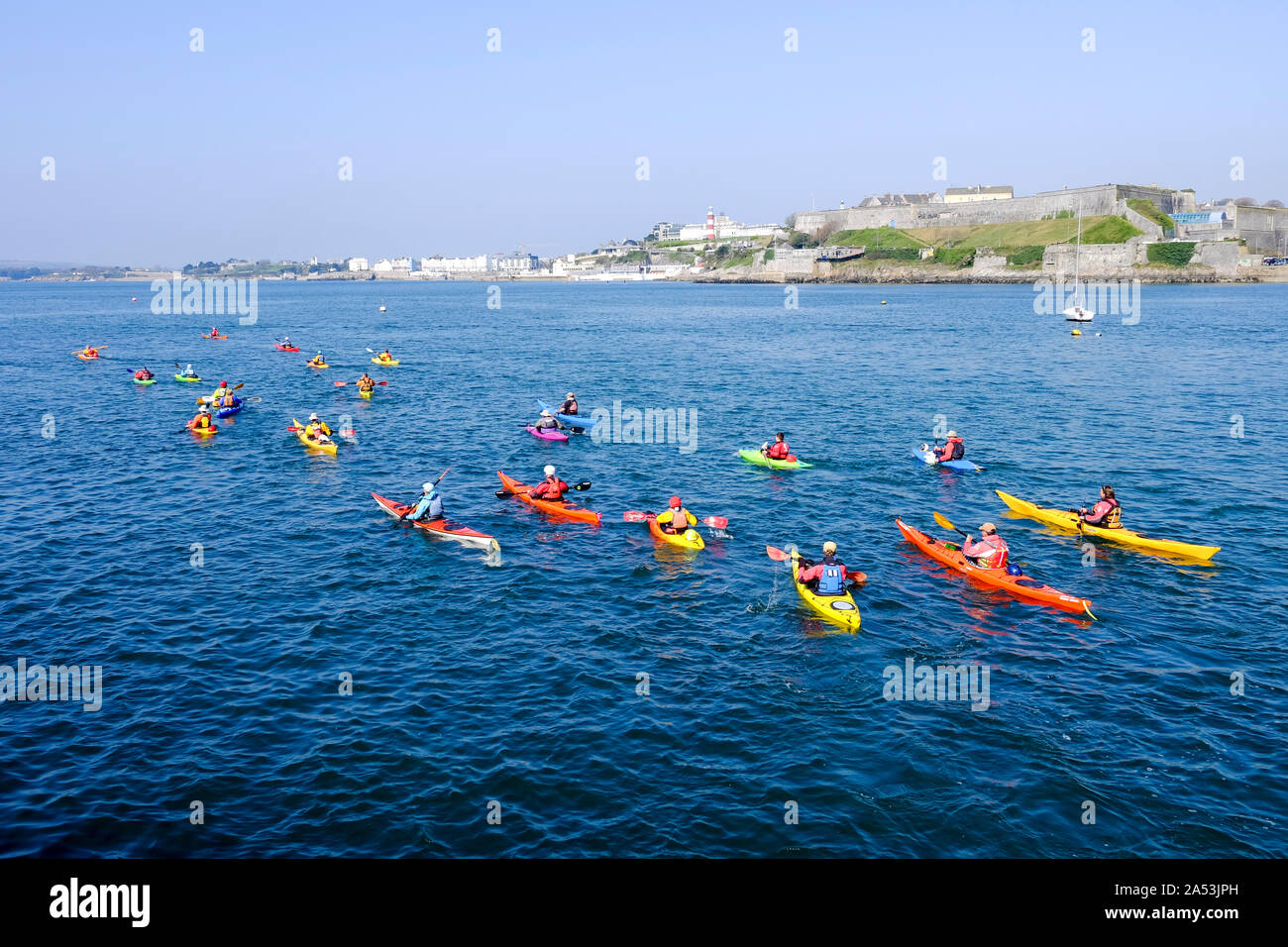 Colourful canoes in Plymouth Sound with the iconic Plymouth Hoe in the background. Stock Photo