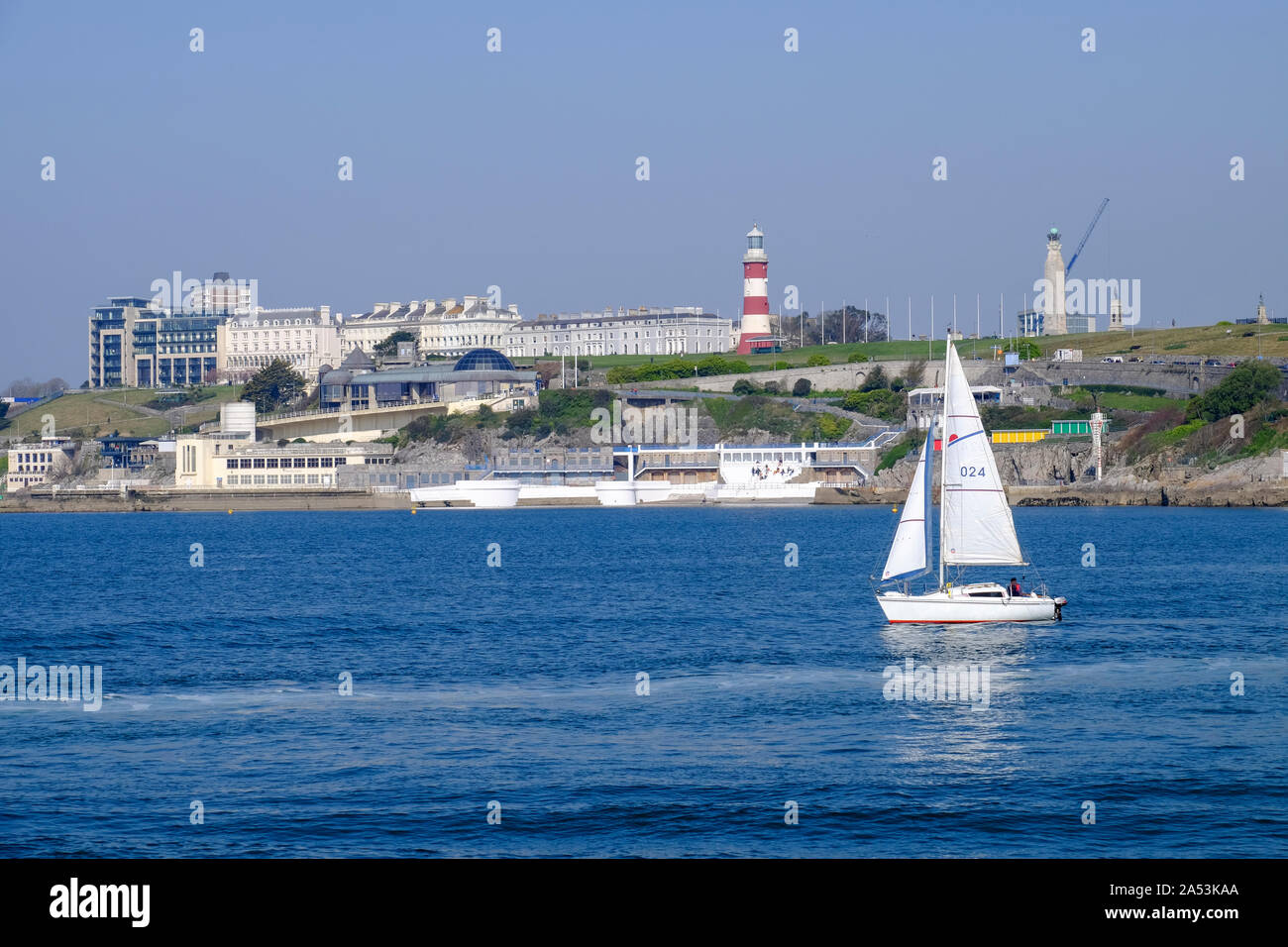 A white yacht sails in Plymouth Sound passing the iconic Plymouth Hoe. Stock Photo