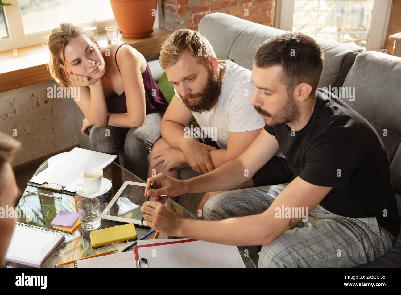 Group of young caucasian office workers meeting to discuss new ideas. Creative meeting. Teamwork and brainstorming. Men and women meet in office to plan their future working. Business concept. Stock Photo