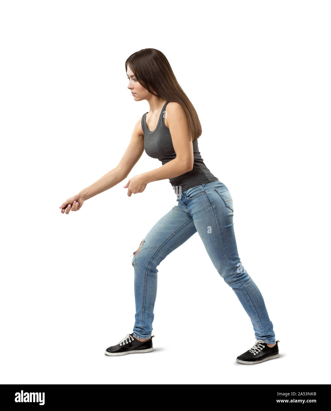 Side view of young fit woman in gray top and blue jeans bending forward  slightly and posing as if holding invisible rope isolated on white  background Stock Photo - Alamy