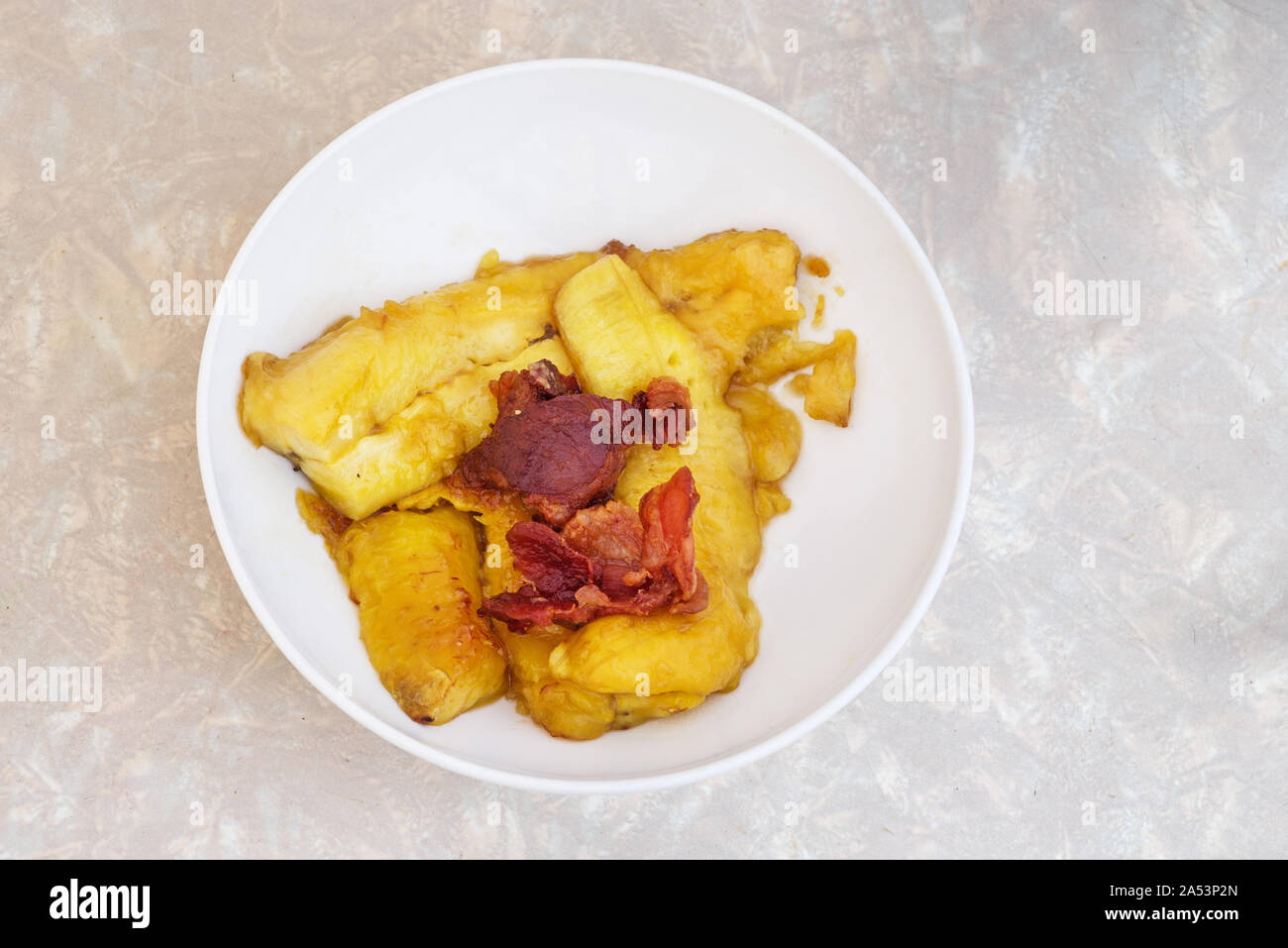 fried plantain with bacon ends in a white bowl Stock Photo