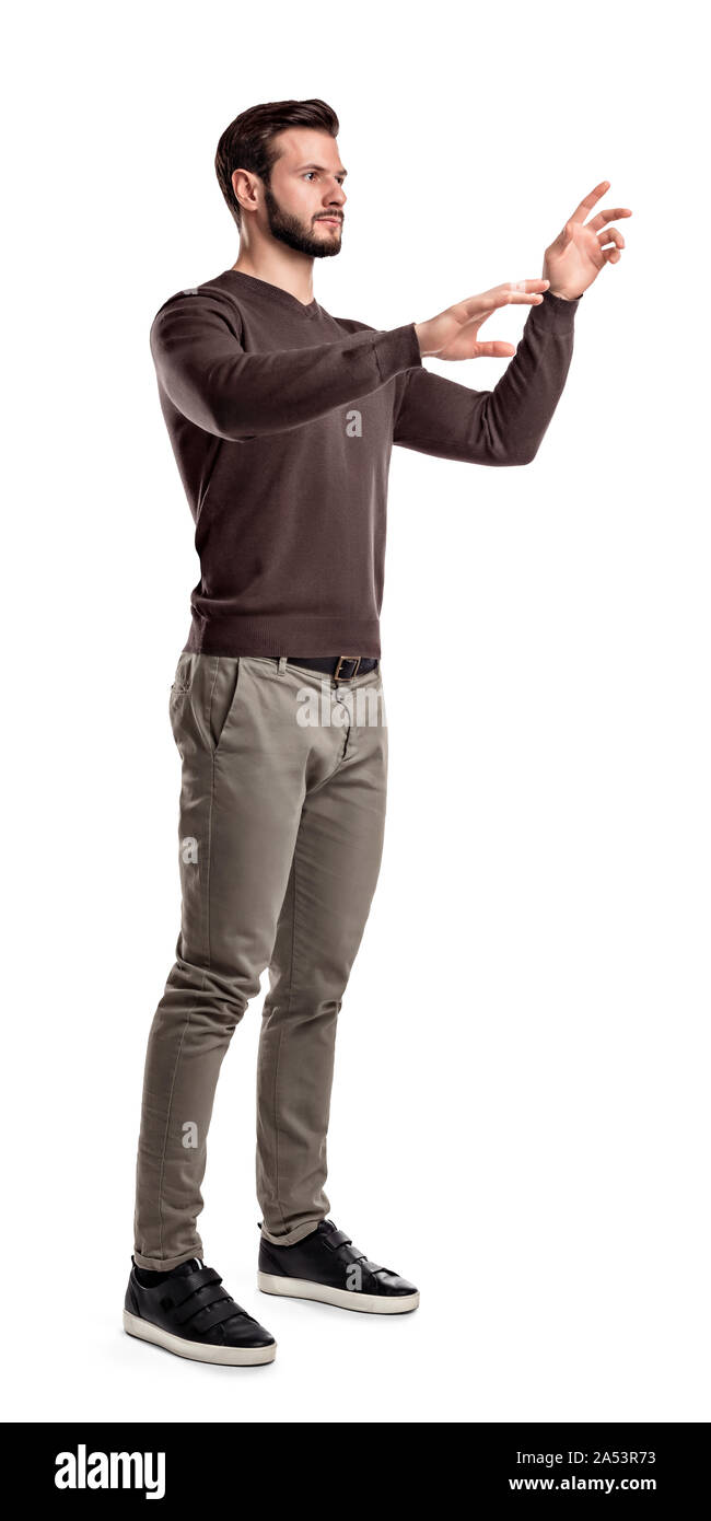 A young man in fashionable casual closes stands on a white background with hands as if pressing invisible buttons. Stock Photo