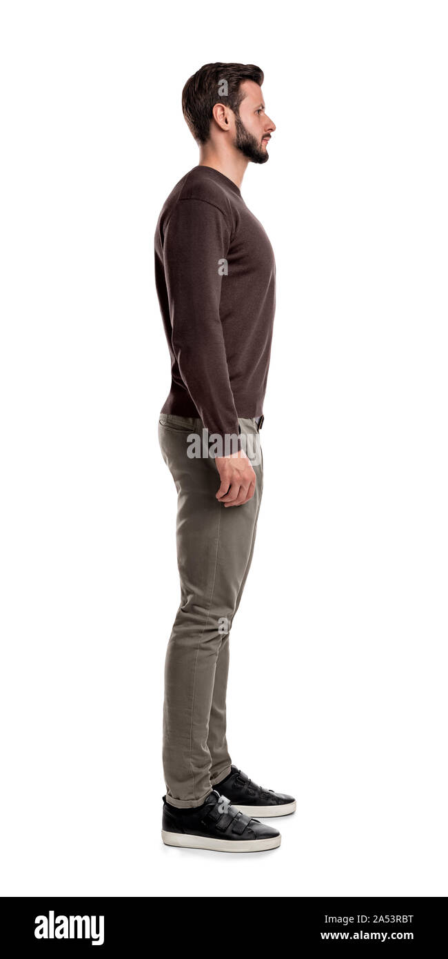 A bearded man in casual clothes stands still with arms hanging straight on his sides in a side view. Stock Photo
