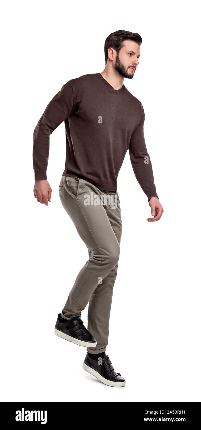 A serious looking man in casual clothes walks down invisible stairs on a white background. Stock Photo