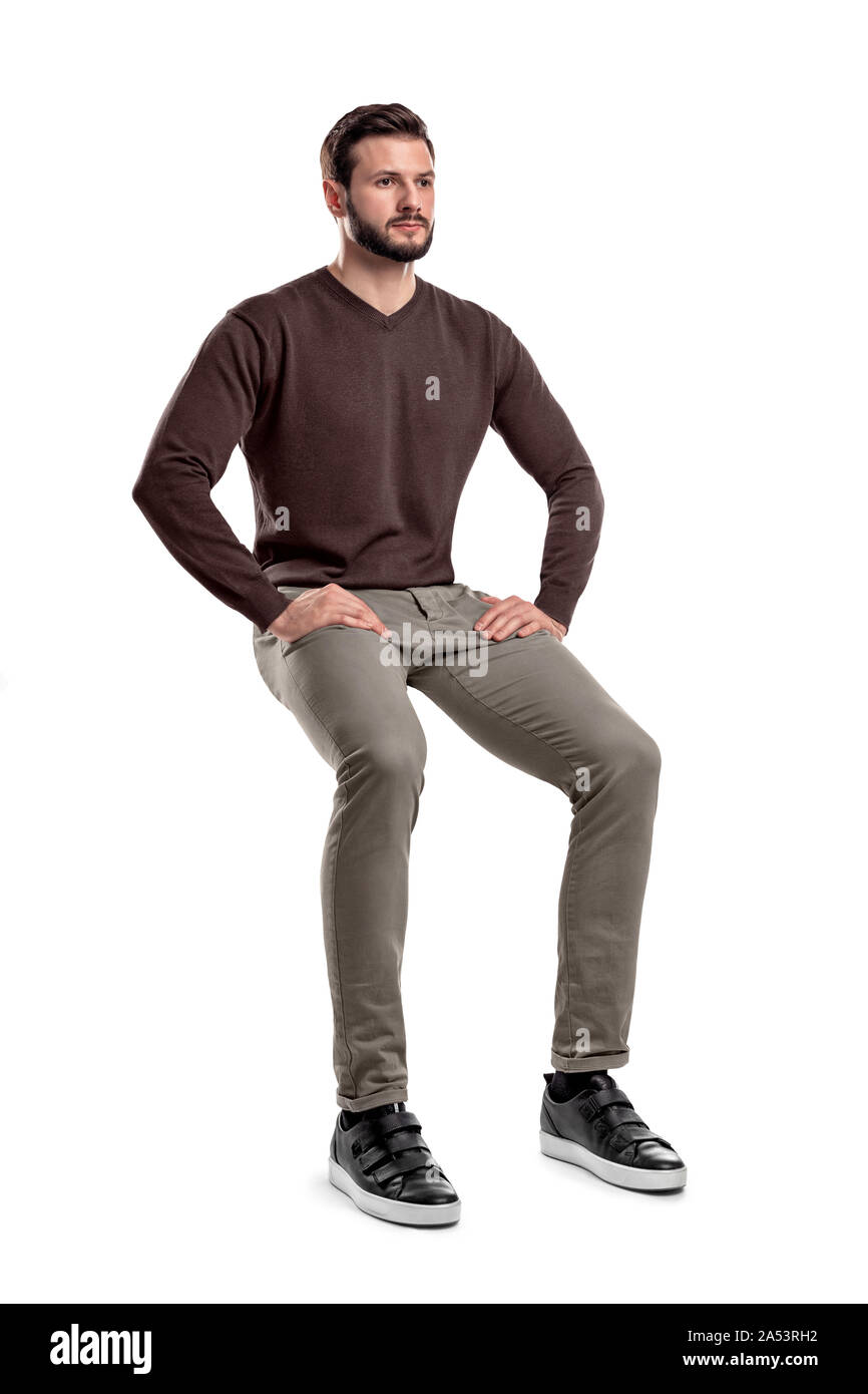 An isolated bearded man in casual wear sits on a white background with ...
