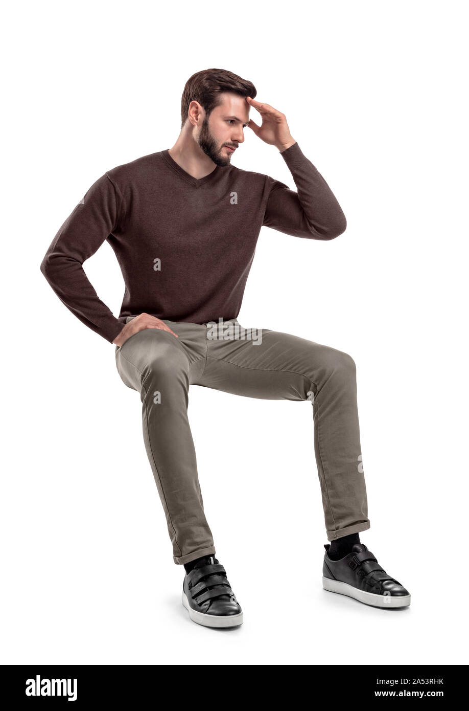 An isolated bearded man in casual wear sits on a white background with ...