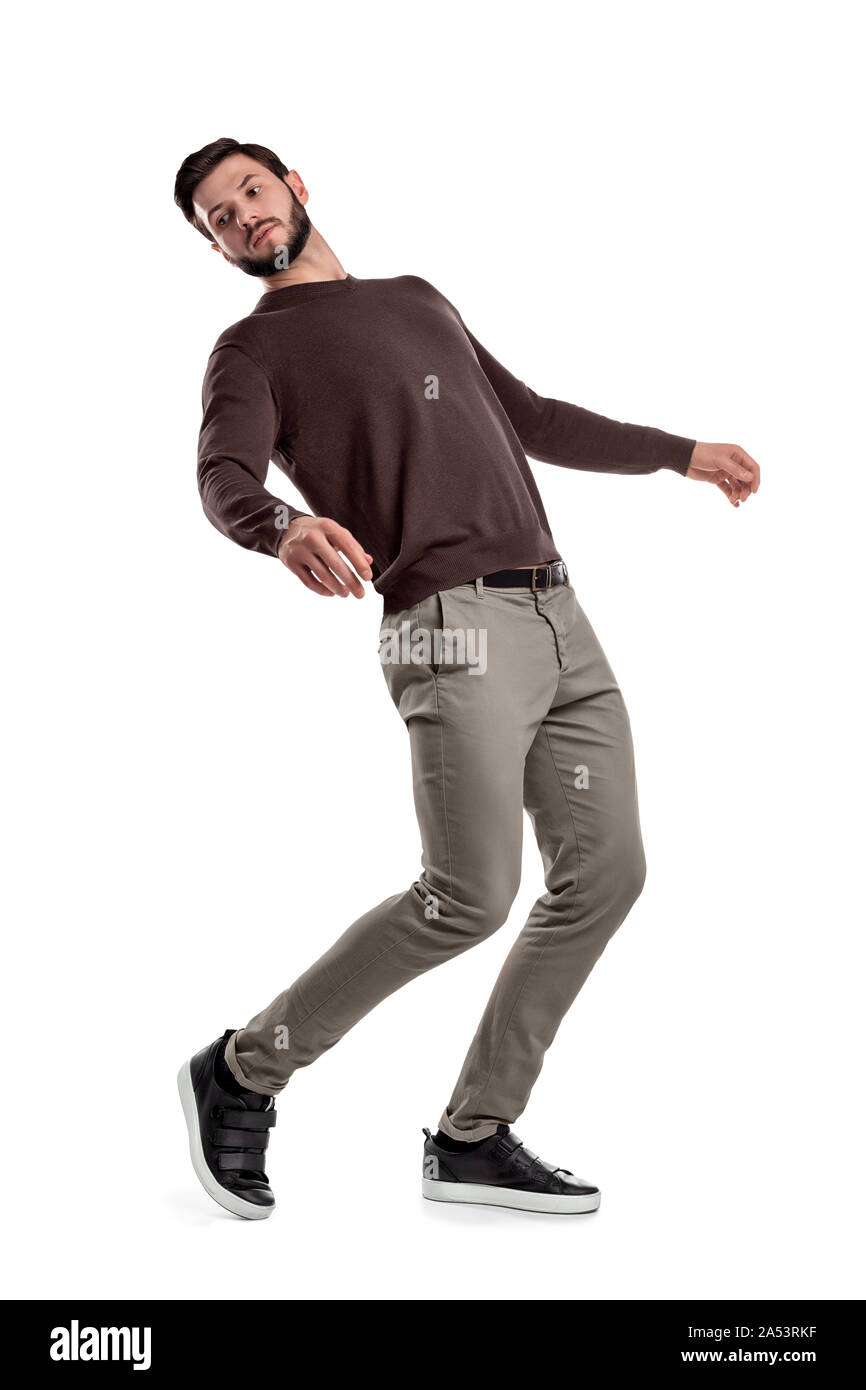 A serious looking bearded man in casual clothes stands in a half-turned view as if almost falling behind. Stock Photo