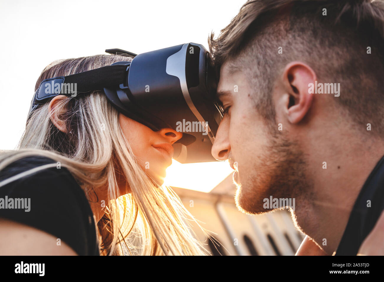 beautiful couple in love hugging and kissing with glasses of virtual reality outdoors