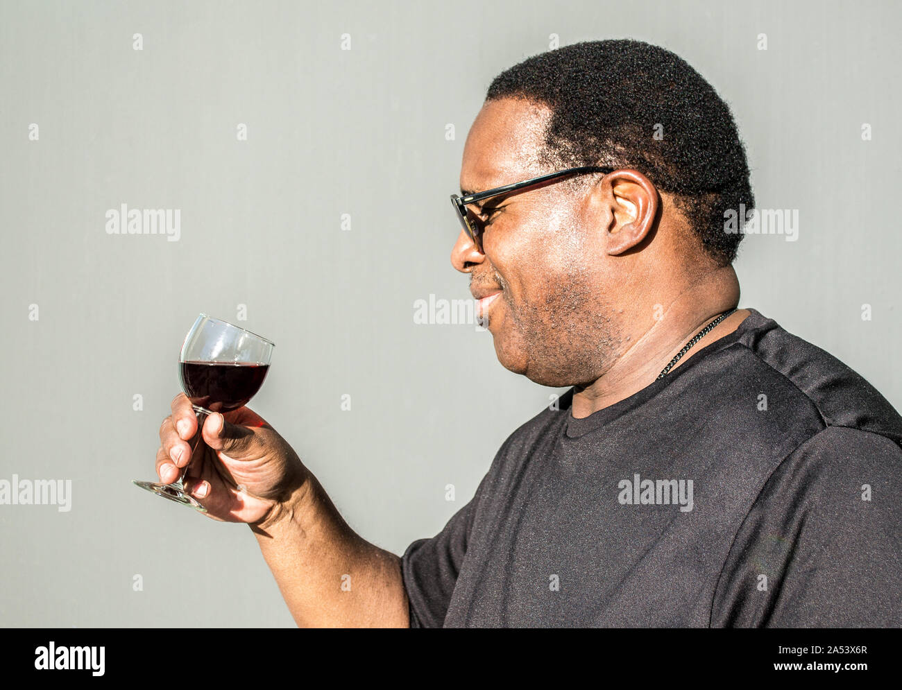 profile of African American man about to drink a glass of red wine ...