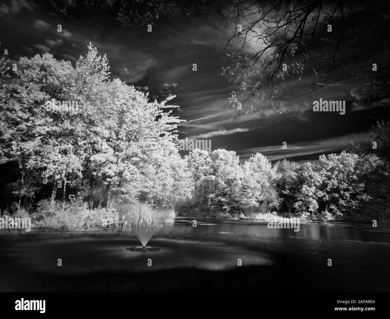 Infrared, fine art photograph of a pond with water fountains Stock Photo