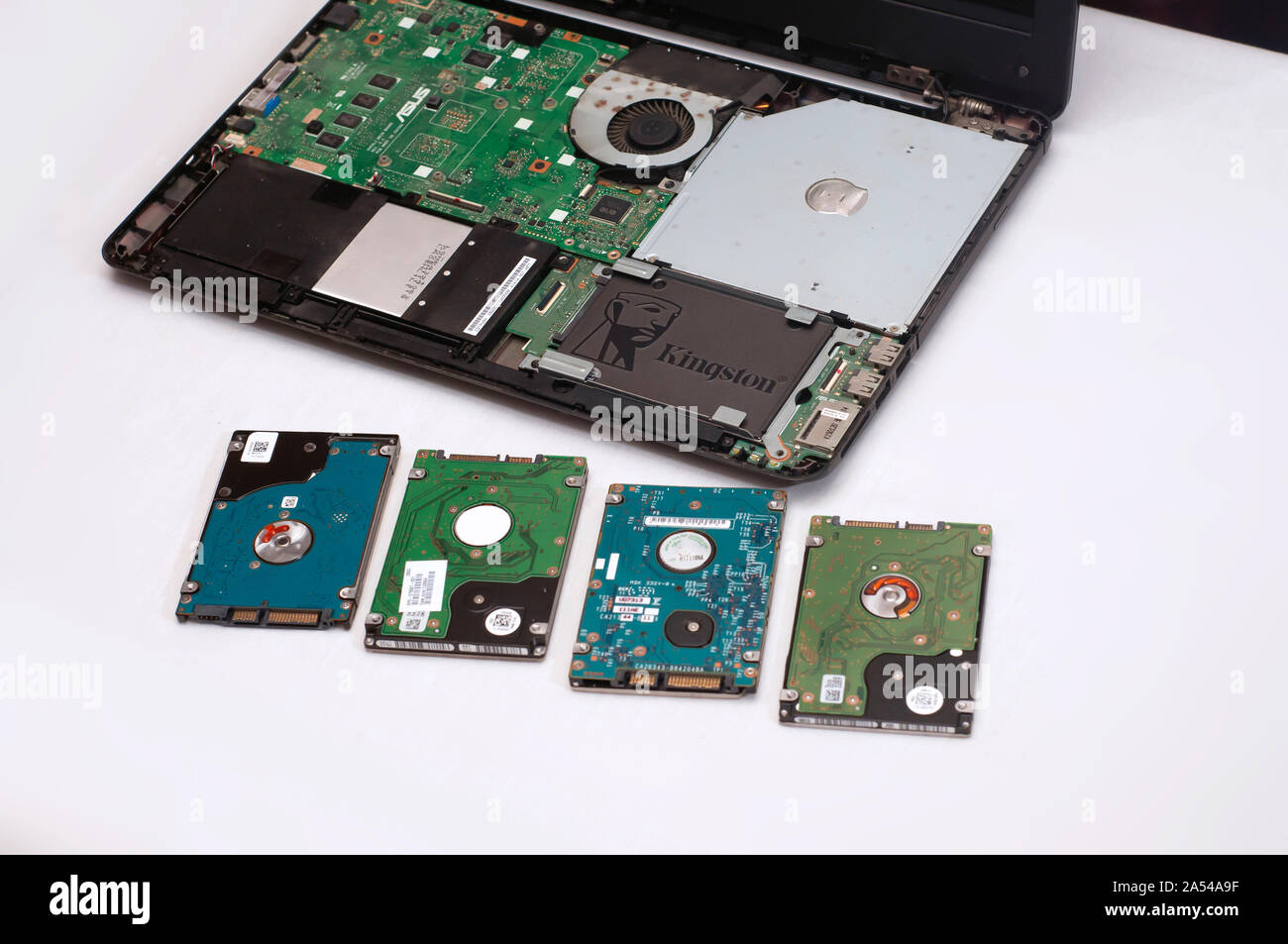 A pile of used HDD next to an open disassembled laptop or notebook computer with an SSD replaced. Stock Photo