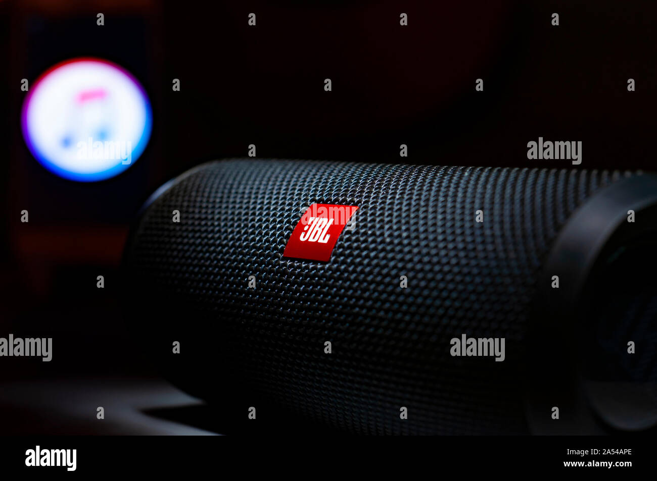 Dramatic close up shot of a JBL Logo with blurred Apple Music App Logo. JBL Flip 4 Bluetooth portable speaker. Stock Photo