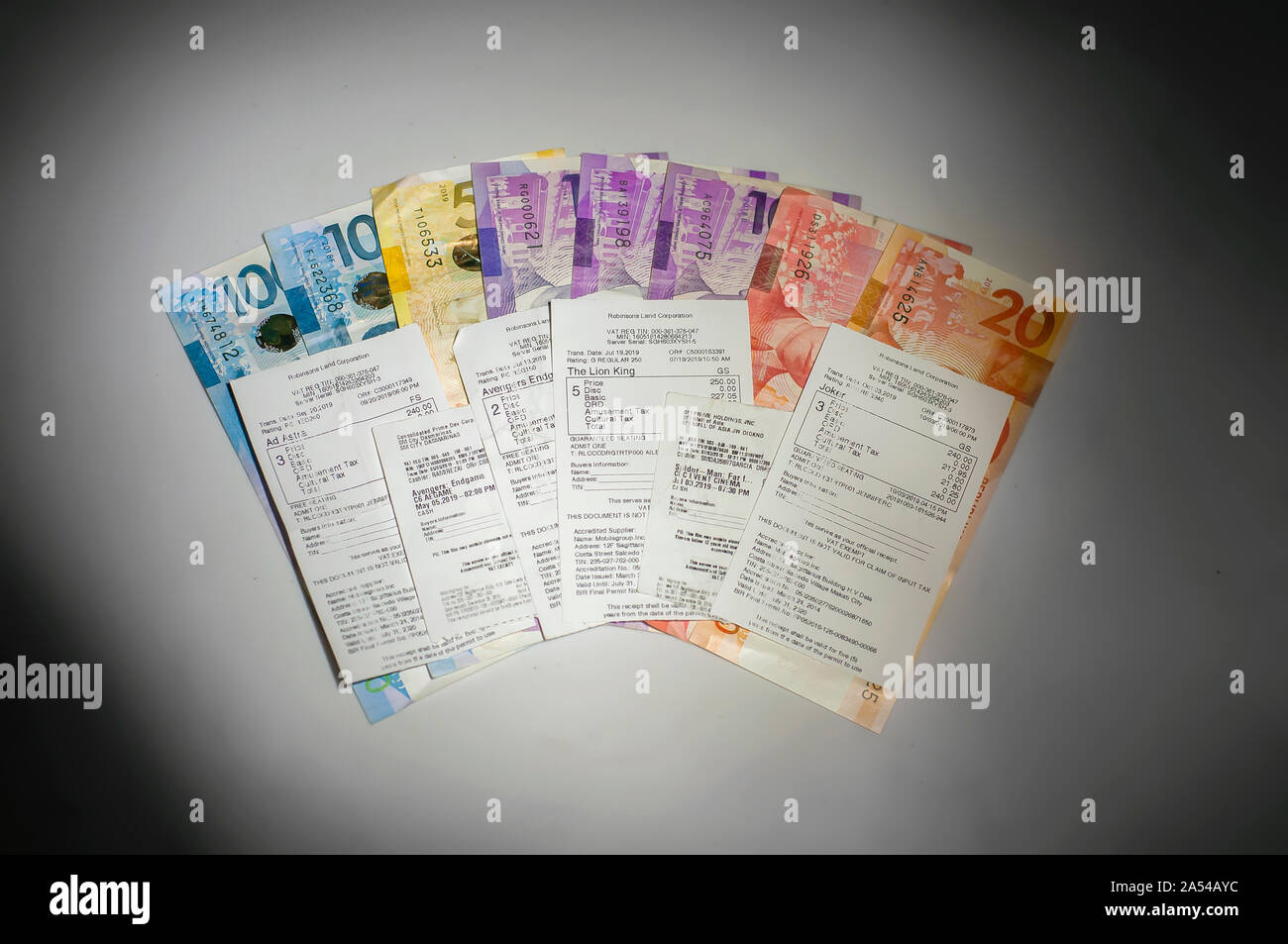 Various Admit One Movie Tickets of Famous Blockbusters of 2019. Movie Tickets placed at the top of Philippine peso bills.  Philippine Peso currency Stock Photo