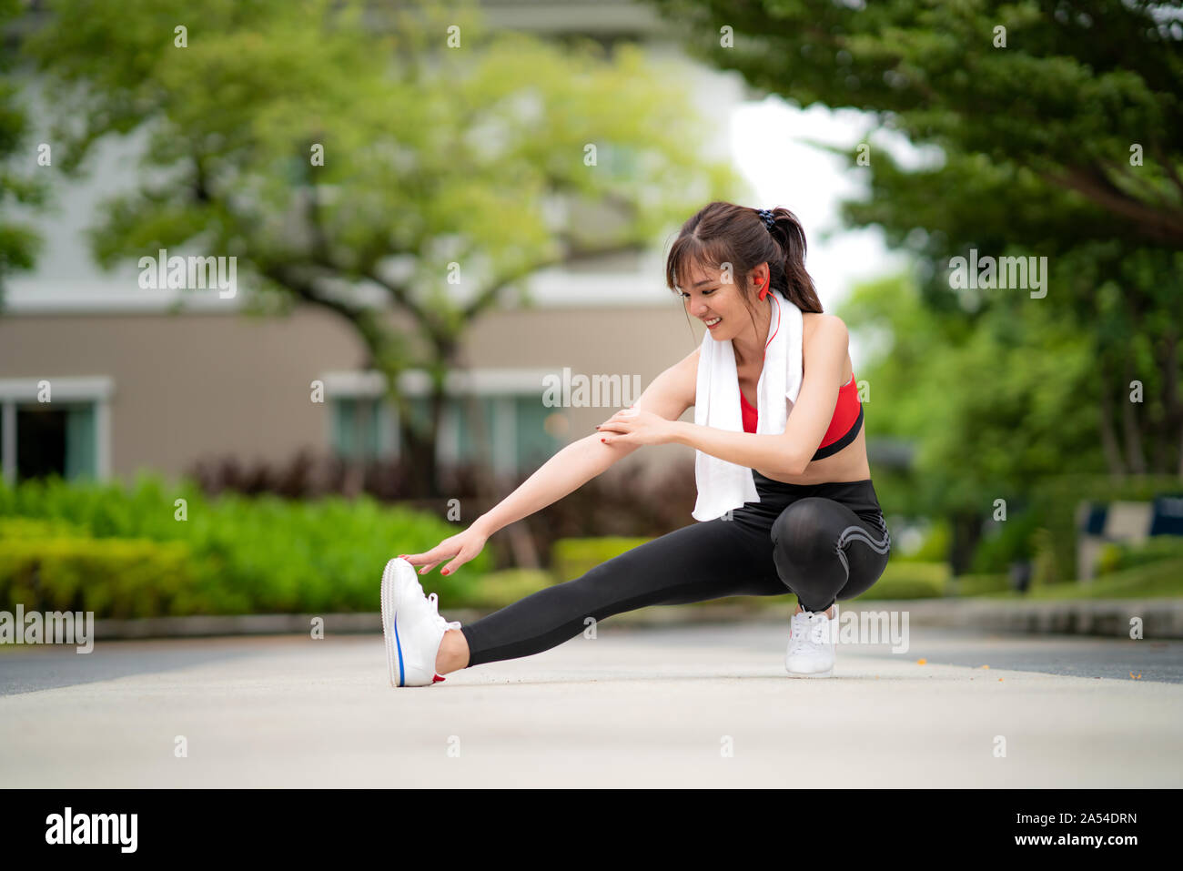 Asian beautiful woman exercising stretch alone in public park in village, happy and smile in morning during sunlight. Sport fitness model Asian ethnic Stock Photo