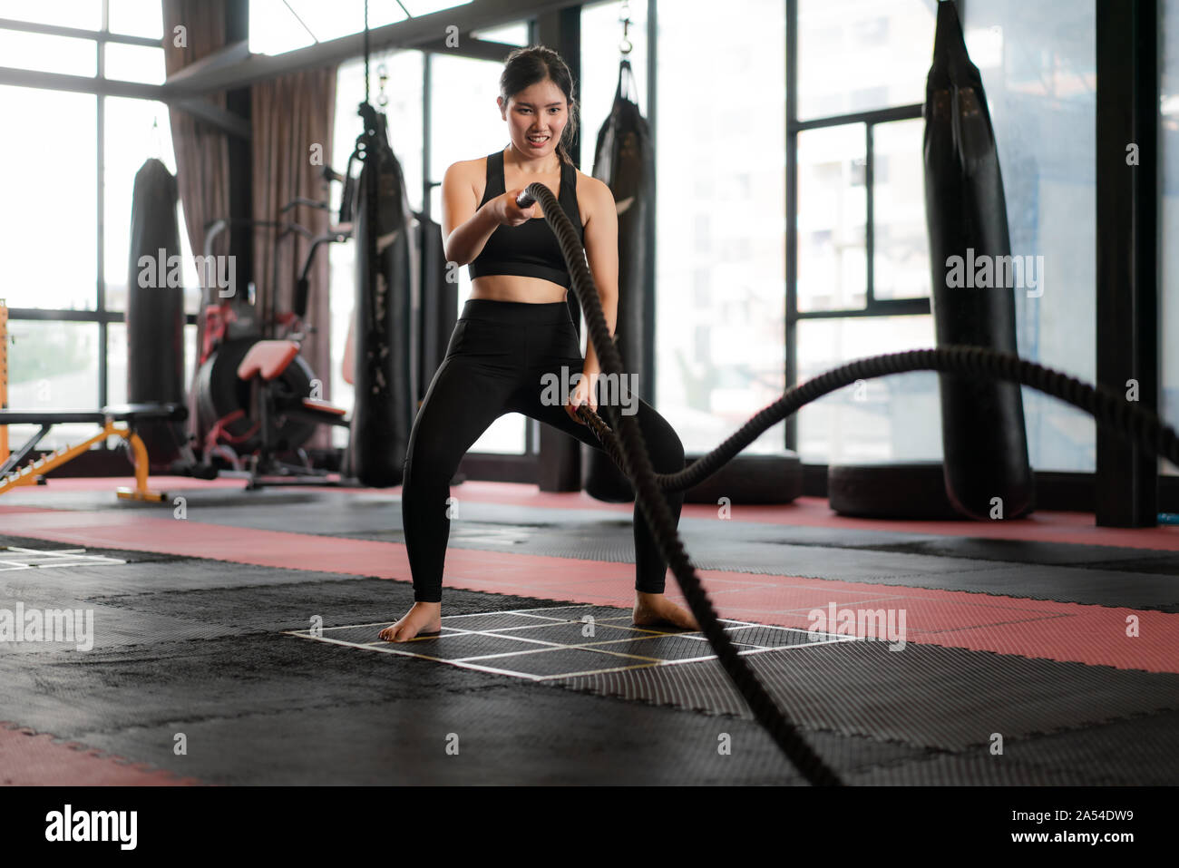 Beautiful Asian Woman with balck battle rope battle ropes exercise in the  fitness gym with boxing bag in background. Sporty fit for healthy lifestyle  Stock Photo - Alamy