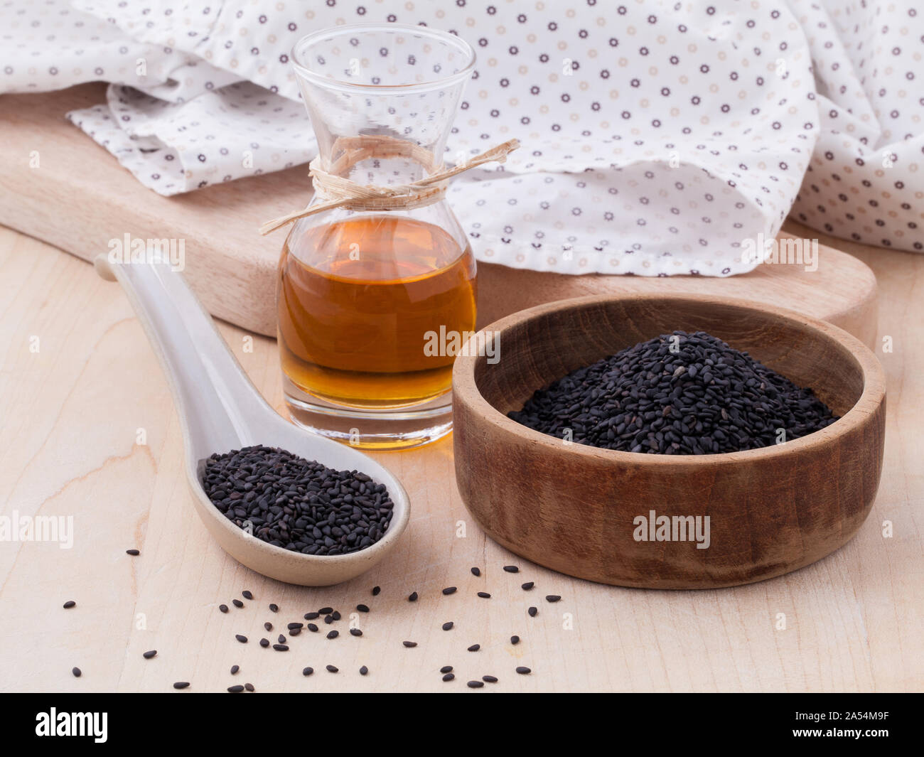 Black sesame oil and sesame seeds set up on wooden table Stock Photo