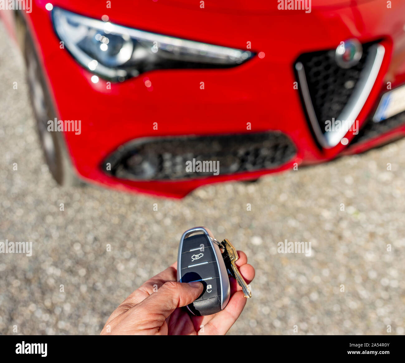 A hand operates the remote control of a beautiful red Italian sports car Alfa Romeo Stelvio Stock Photo