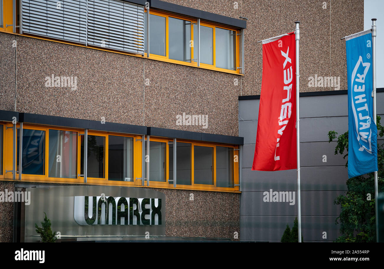 17 October 2019, North Rhine-Westphalia, Arnsberg: The company logo hangs on the outer facade of the weapons manufacturer Umarex, in front of which a flag of the weapons brand Walther is flying. Because for years he is said to have smuggled pistol parts from a weapons manufacturer's factory, assembled and sold them, a 47-year-old man is now on trial in Arnsberg, Sauerland. Since 2015, the long-time employee of the Arnsberg-based sporting weapons manufacturer Umarex has been reported to have repeatedly stolen design drawings and weapon parts from his former employer and assembled them into func Stock Photo