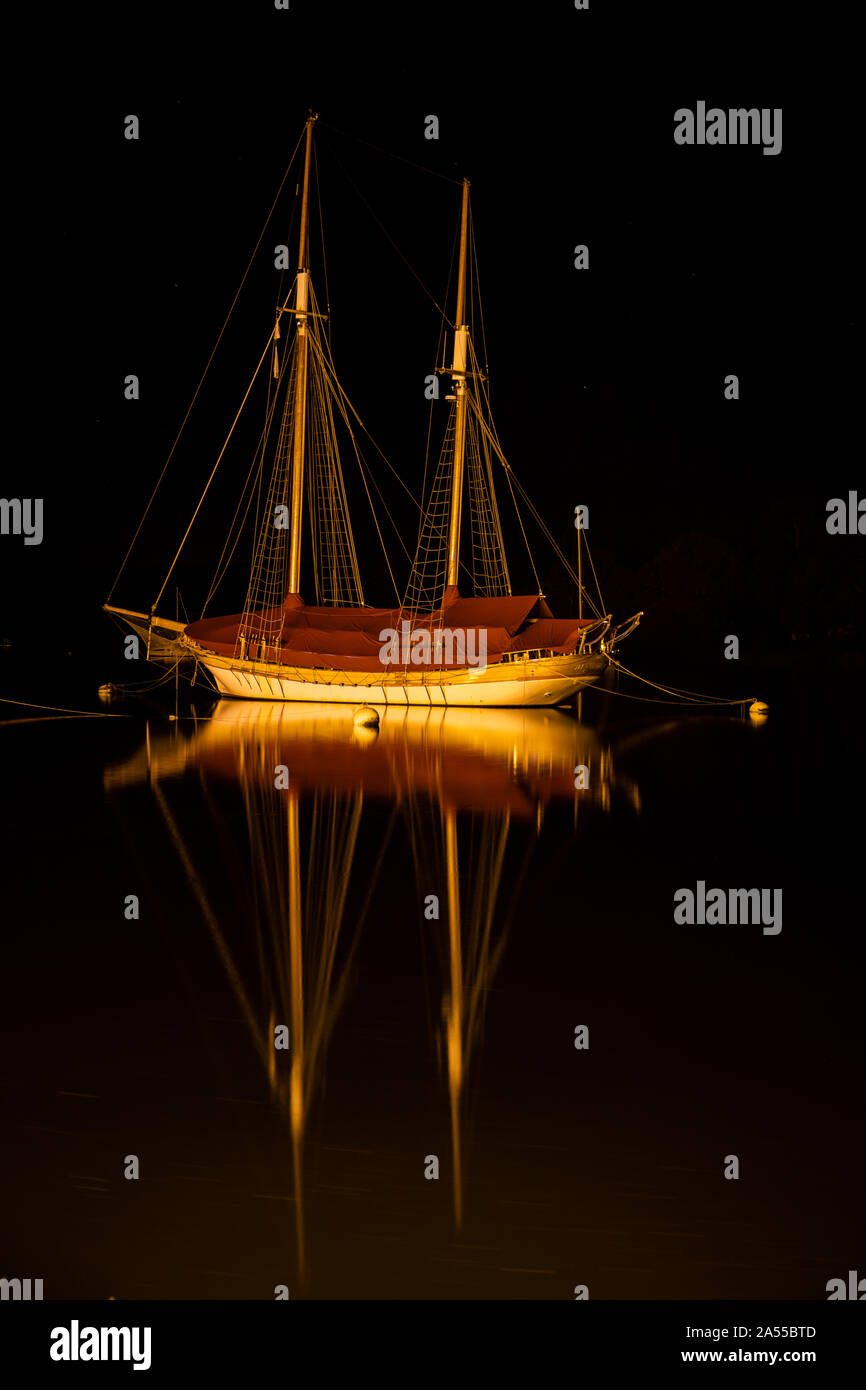 Large Classic Boat on a mooring on the Vilaine river illuminated at night by the sodium lighting Stock Photo