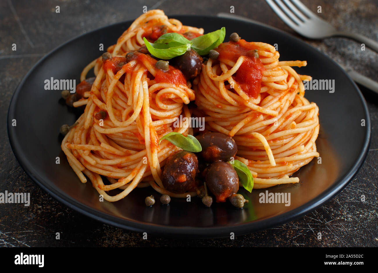 Pasta alla puttanesca - Spaghetti with tomato sauce olives and capers Stock Photo