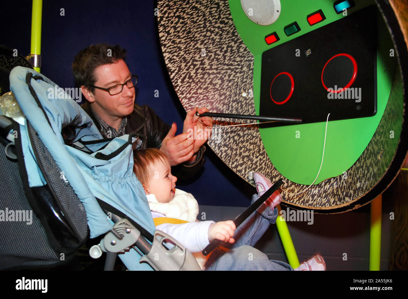 Girl toddler enjoying a drum machine with her dad in 'The Garden' at