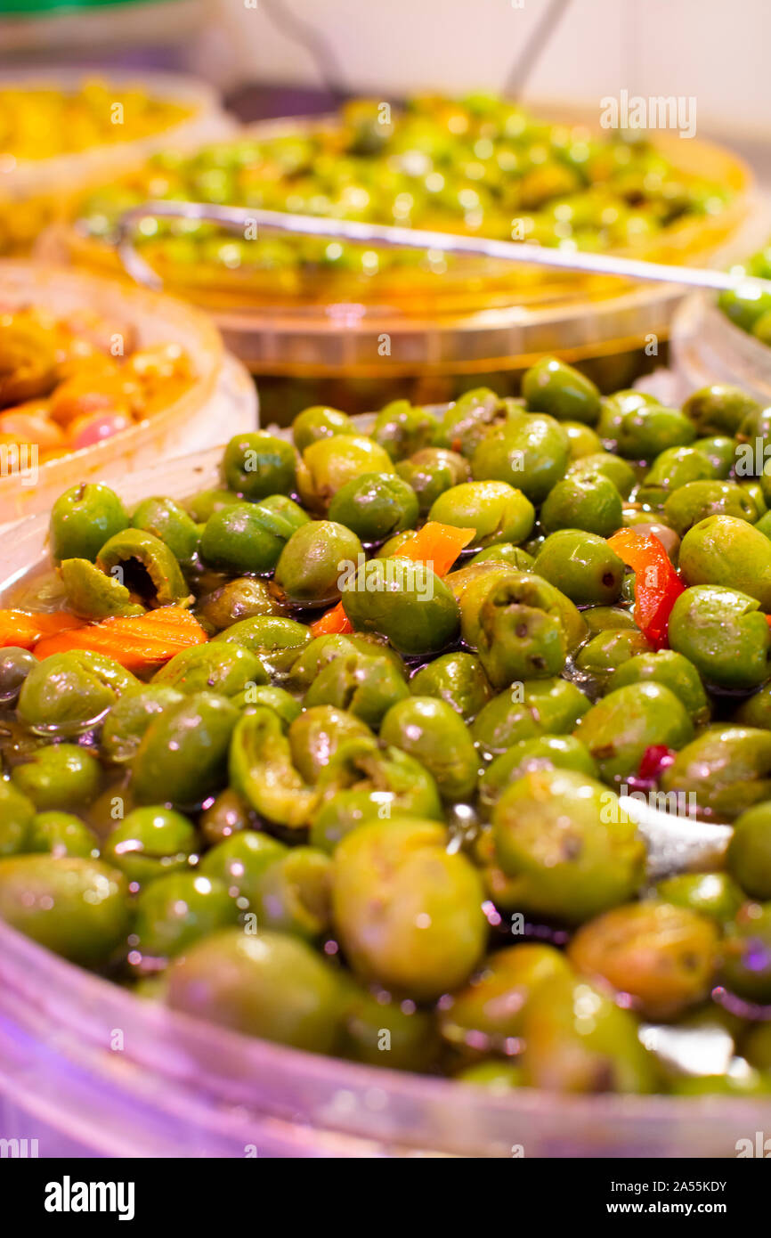 Homemade pickled green olives with garlic and spices in bucket on spanish market Stock Photo