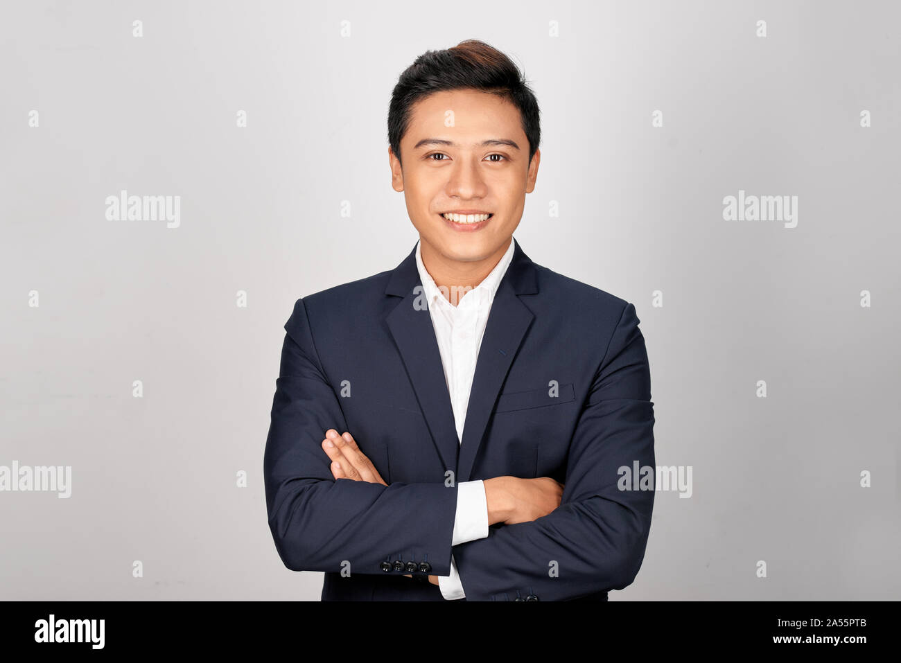 Happy Asian young businessman standing cross-armed on white background Stock Photo