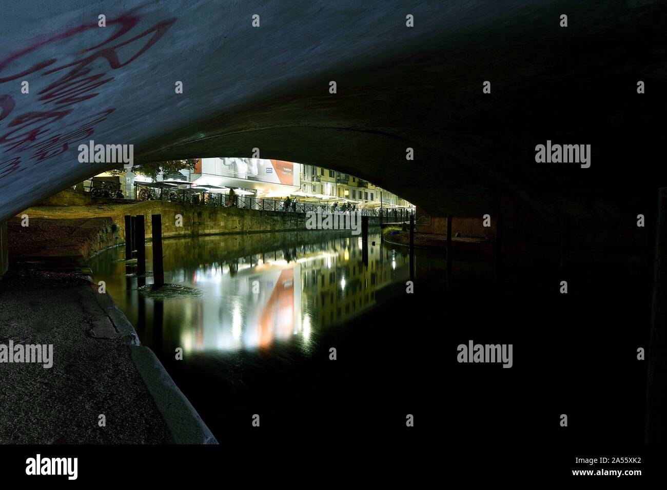 Horizontal shot of beautiful buildings reflected in the lake under a concrete bridge in Milan, Italy Stock Photo
