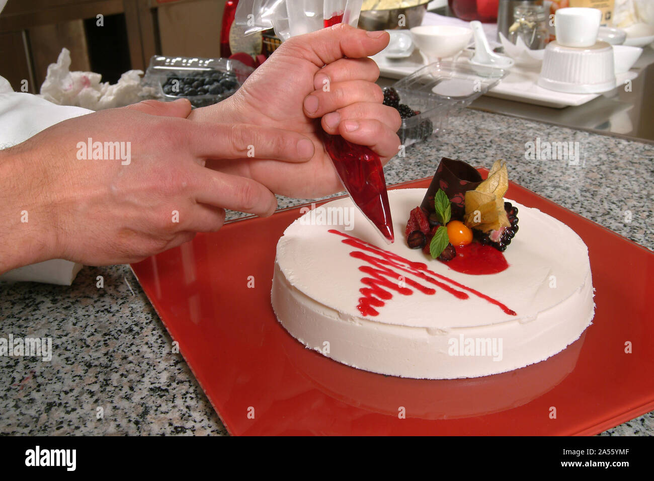 Pastry chef decorates a Bavarian cream  cake. Stock Photo