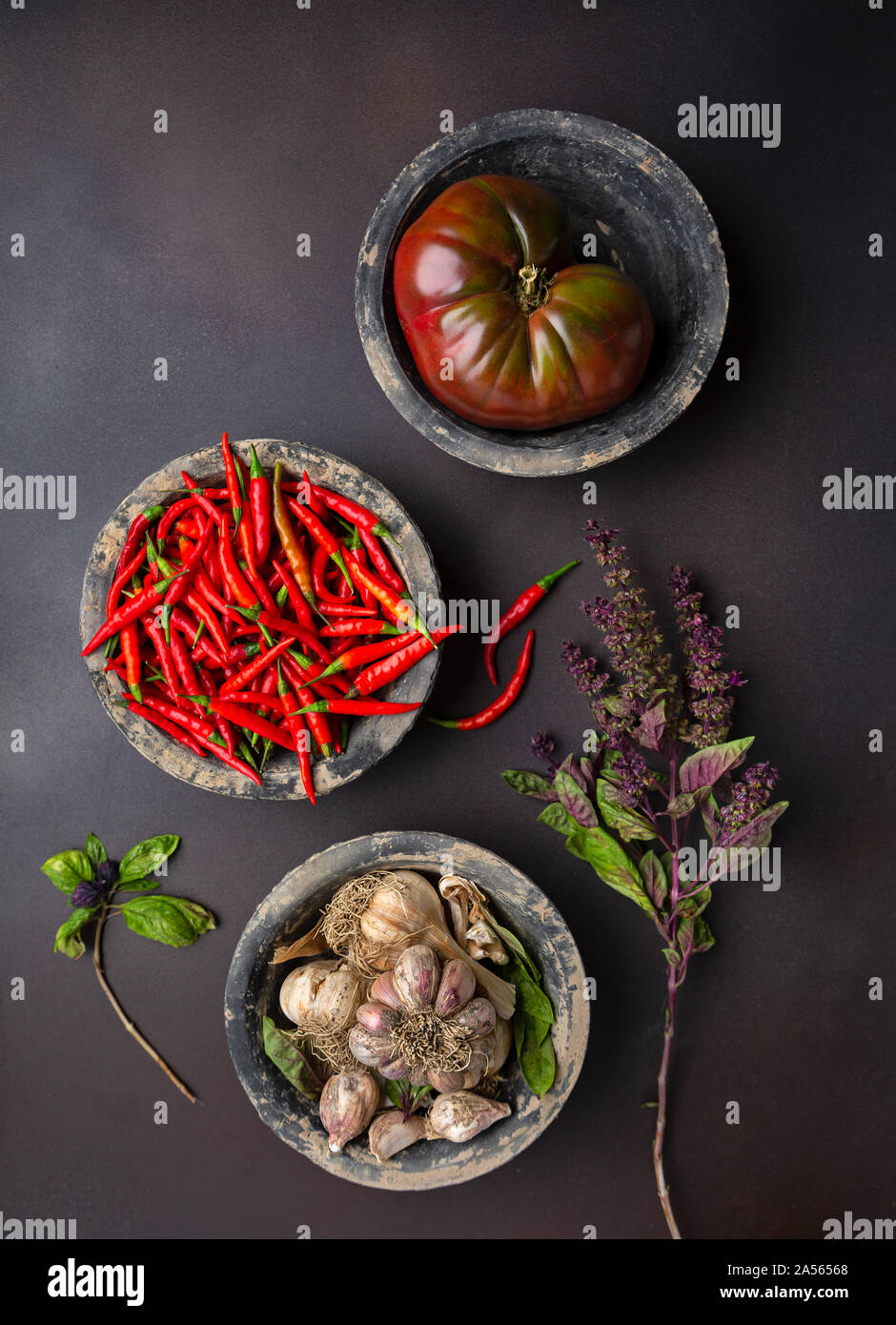 Overhead view of three rustic bowls of tomato, chili peppers, garlic