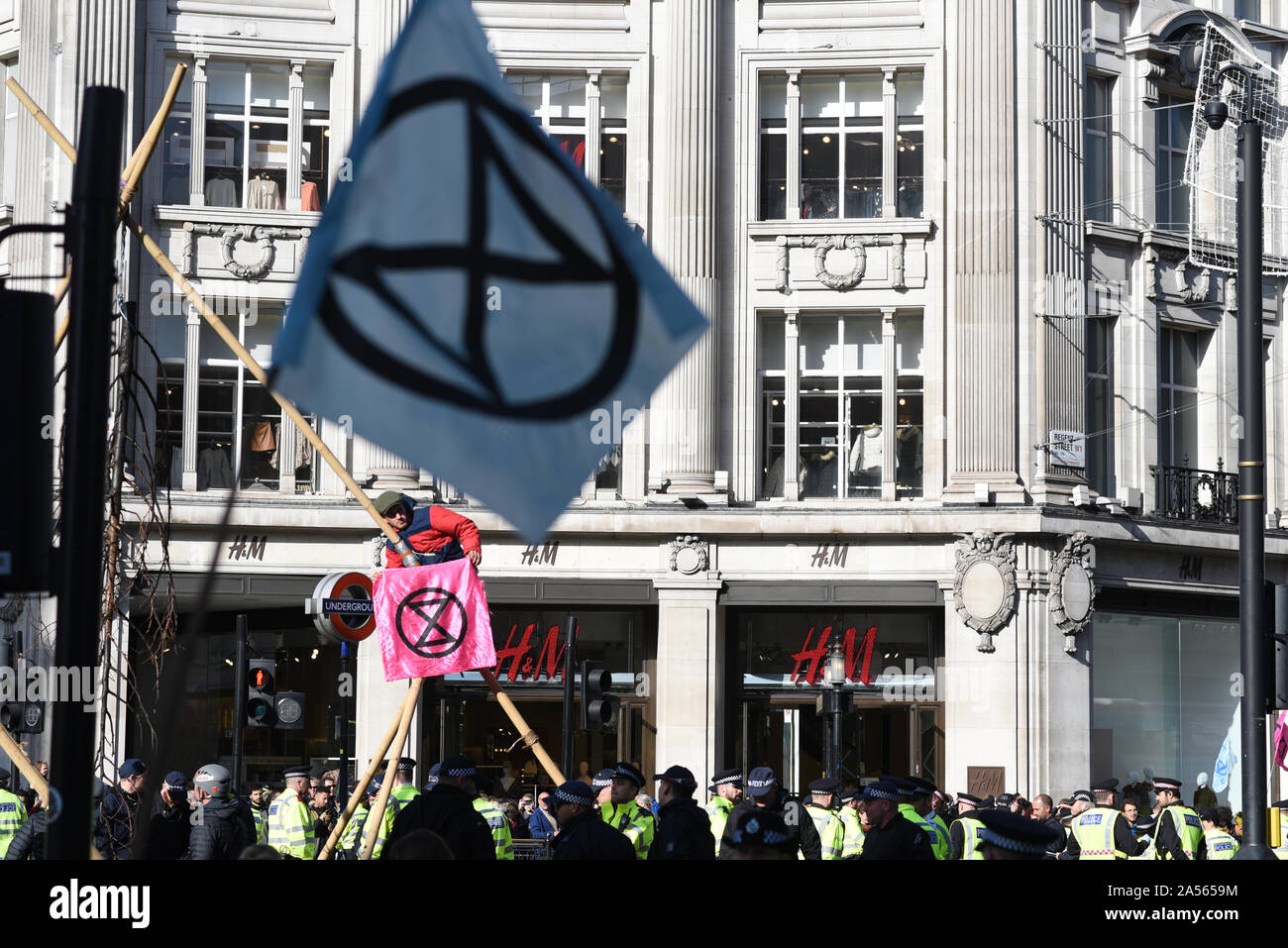 London, UK. 18th Oct, 2019. A climate change activist holds a flag with the Extinction Rebellion logo as he sits in a makeshift structure occupying London’s Oxford Circus. Credit: Kevin Shalvey/Alamy Live News Stock Photo