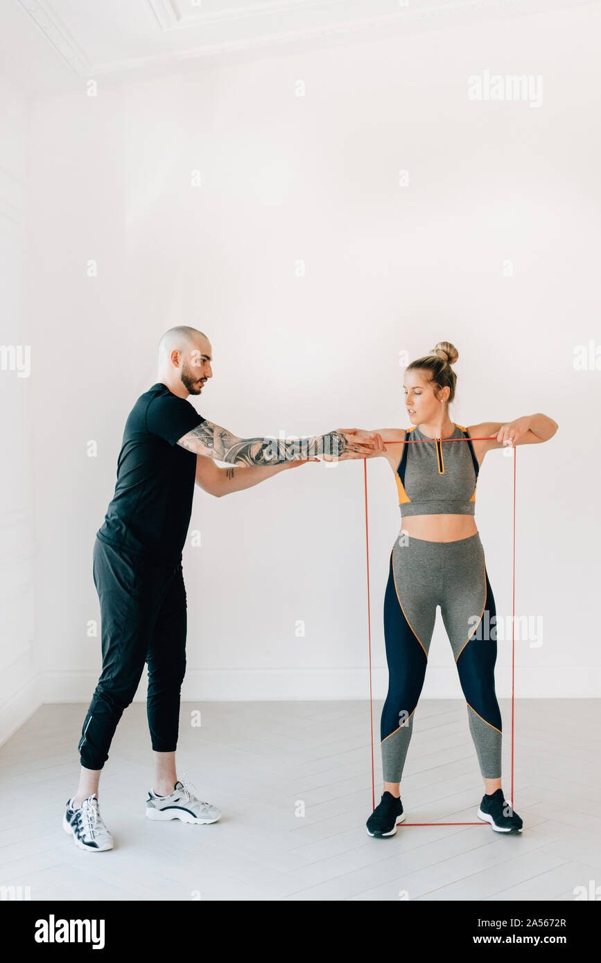 Fitness instructor teaching woman using resistance band in studio Stock Photo