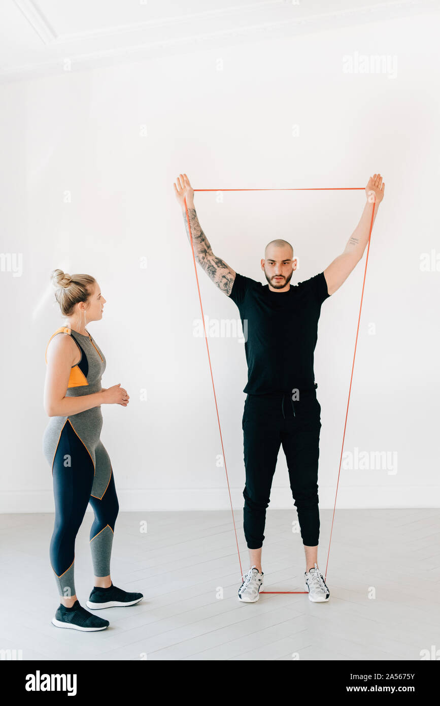 Woman observing fitness instructor using resistance band in studio ...