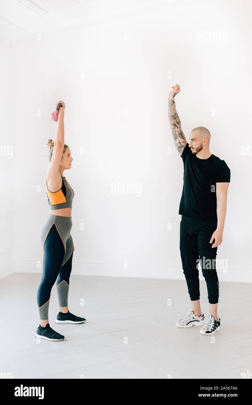 Fitness instructor teaching woman lifting kettlebell in studio Stock Photo