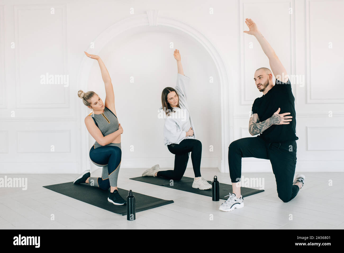 Fitness instructor teaching women stretching arm in studio Stock Photo
